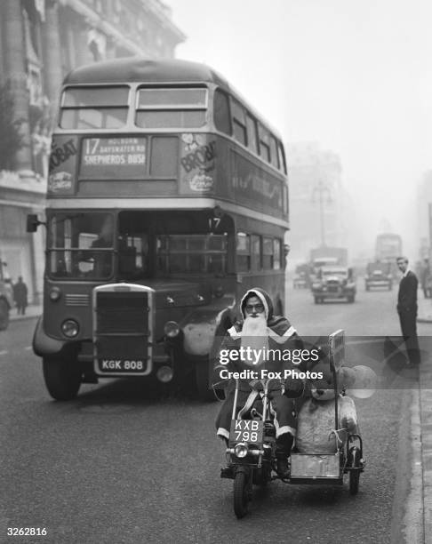 Santa Claus rides a motorbike with a sidecar down Oxford Street, London.