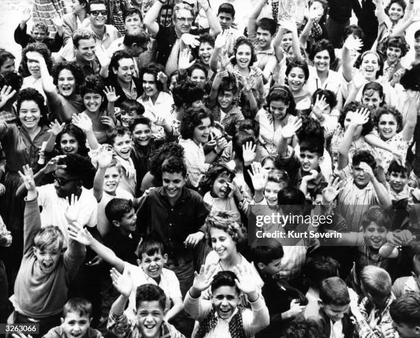 Crowd of happy cheering children rescued from Castro Island by the Catholic Welfare Organisation, at a refugee camp south of Miami waiting for future...