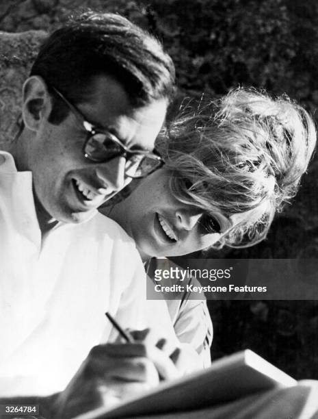 French film director Roger Vadim and his wife Annette, drawing something amusing.