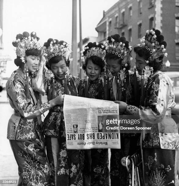 Group of five women dressed in traditional Chinese clothing reading one newspaper between them in Chinatown, San Francisco.