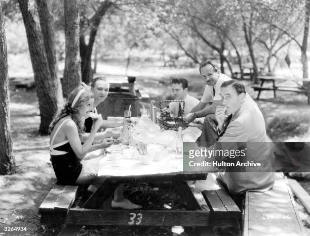 Peggy Shannon, the Paramount star takes a picnic lunch with Lee Tracy, Freddy Wilcox, assistant director, Hal Ronson, the cameraman and director...