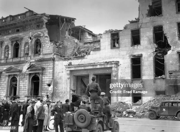 Jeep with British and American soldiers outside the ruins of the Chancellery in Berlin.