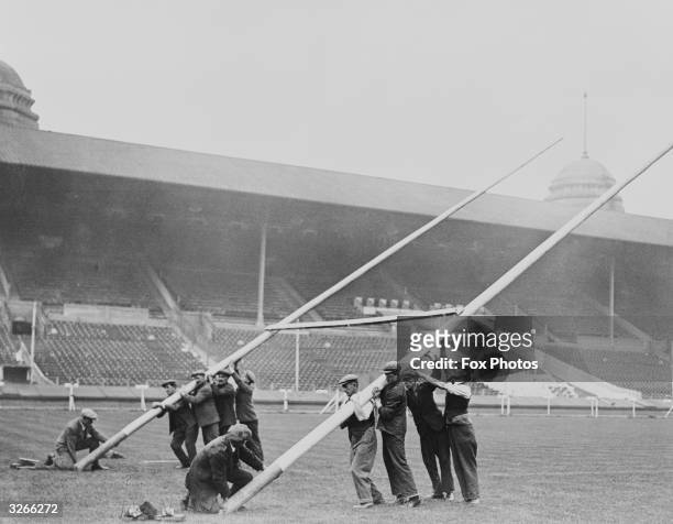 Workmen raise the rugby goalposts at Wembley Stadium in preparation for the Rugby League Cup Final.