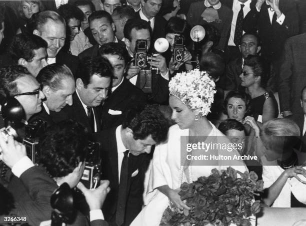 Elizabeth Taylor the American leading lady, in the midst of a crowd of admirers and reporters, with her fourth husband, Eddie Fisher the American...