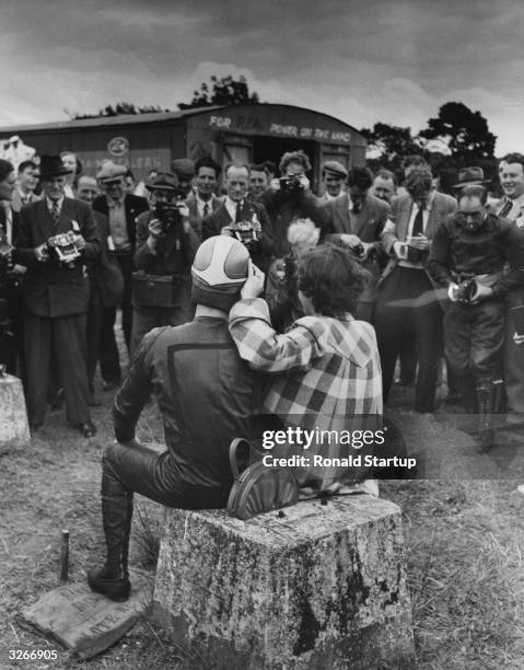 Motocycle racer Geoffrey Duke being photographed with his fiancee Pat Reid after winning a major race in Ulster. Original Publication: Picture Post -...