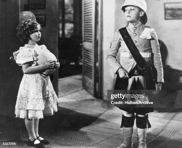 Shirley Temple, the child prodigy in a scene with Douglas Scott from 'Wee Willie Winkie' about a small girl becoming the mascot of a British regiment...
