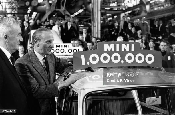 Turkish born automobile designer Sir Alexander Issigonis hails the one millionth mini car with production manager Bill Edwards, watched by factory...