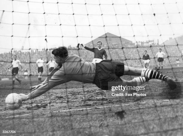 Fulham goalkeeper Hewkins gets his hands to the ball but fails to stop Manchester United's Quixall from scoring during their league match at Craven...