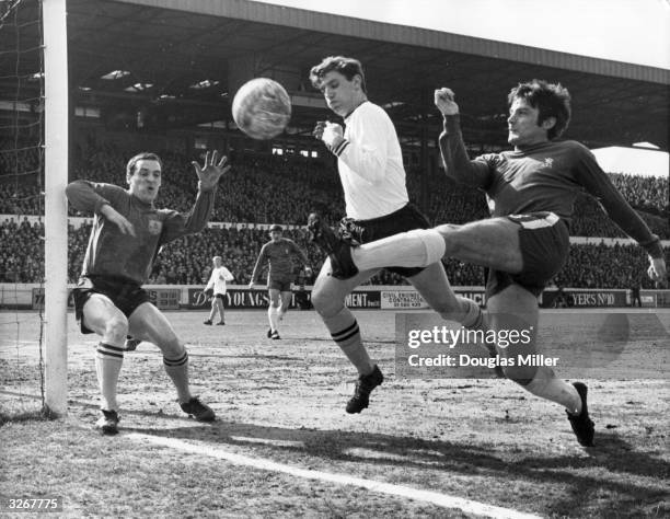 Bobby Tambling of Chelsea tries a shot at goal from an acute angle, as Latcham of Burnley attempts to block him and goalkeeper, Thomson, covers his...
