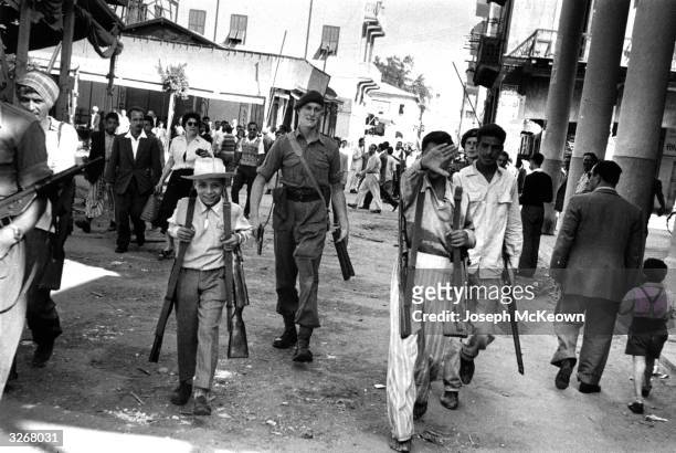 British soldier and some armed Egyptians in the streets of Port Said after the bombardment and air attack. Original Publication: Picture Post - 8735...