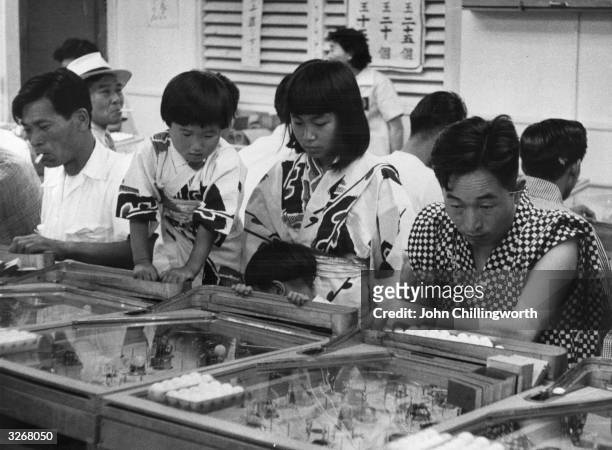 People of Hiroshima playing in a pin-ball saloon, 10 years after the Atomic bomb burst. Original Publication: Picture Post - 7849 - Hiroshima - pub....
