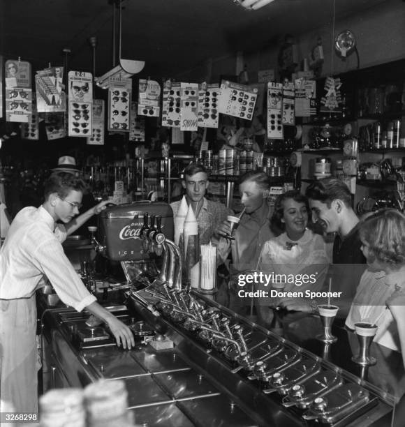 Teenagers enjoy sweet drinks at a drugstore's soda fountain.