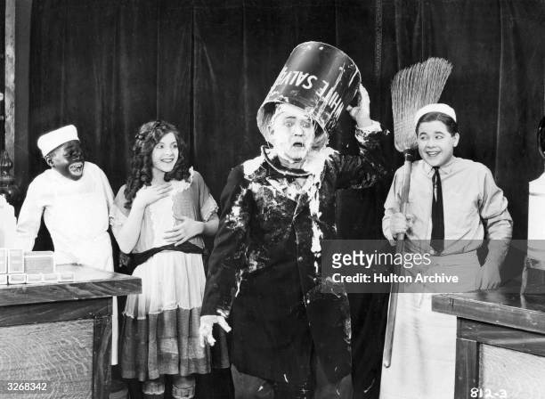 Actors 'Bubbles' , Martha Sleeper (1907 - 1983 and Buddy Messinger watch a Fatty Arbuckle look-alike pour a bucket over his head in a still from a...