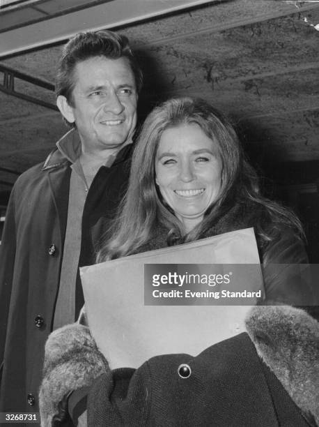 American country singer and songwriter Johnny Cash at London Airport with his wife June Carter Cash , of the Carter Family group.