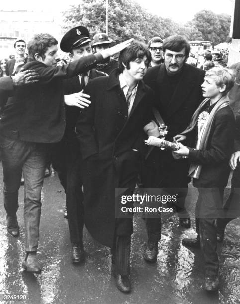 Pop singer and bass player Paul McCartney of The Beatles is besieged by fans as he arrives at Wembley to see the FA Cup Final football match between...