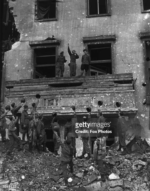 American Corporal Russell M Ochwad impersonates Hitler on the balcony of the bombed out Chancellory, saluting some troops below.