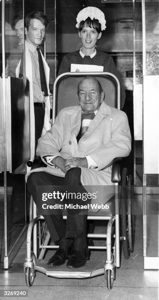 Noel Coward leaving St Thomas's Hospital, London, in a wheelchair after an 18 day stay following an attack of pleurisy.