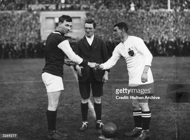 Watched by the referee, G Kay, captain of West Ham United, and Joe Smith, captain of Bolton Wanderers, shake hands before the kick off of the first...