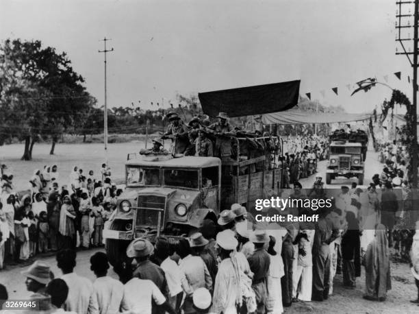 Crowds lining the streets watch as Indian troops drive by in trucks in the Ladakh region of northern India during border clashes between India and...