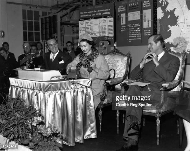 The Queen picks up the receiver and dials the number of the Lord Provost of Edinburgh, making the first trunk call on the Bristol Telephone Exchange.