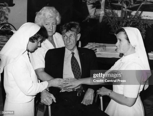 English faith healer, Mrs Mary Rodgers , places her hand on a patient with a slipped disc during one of her faith healing sessions at St John of God...