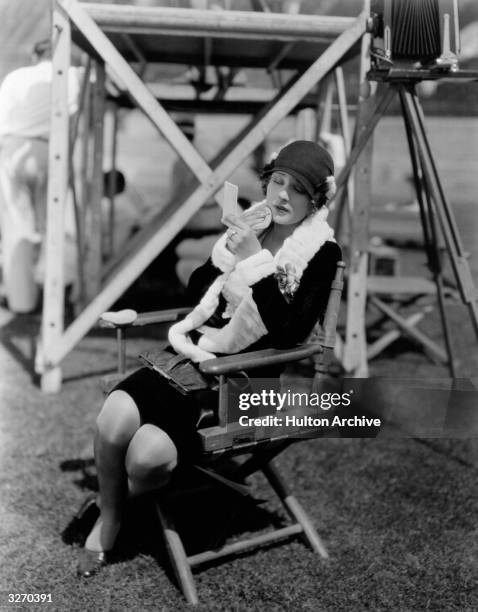 Dolores Costello the American silent screen heroine who worked for Warner Brothers. She is outside on location, applying powder to her face, between...