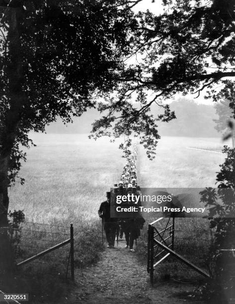 Racegoers walking through a field on their way from the railway station to the Royal Enclosure at Ascot.