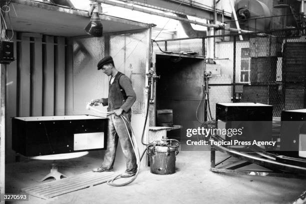 An employee spray paints the steel cabinet of a refrigerator at the Electrolux Ltd factory in Luton.