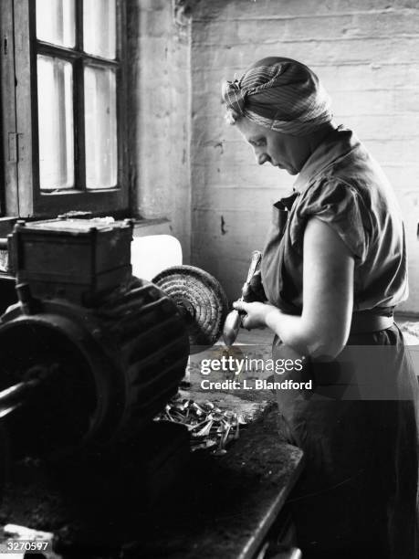 An employee at a factory in Sheffield polishes a spoon on a wheel, one of a sequence of abrasive operations in the cutlery-making process.