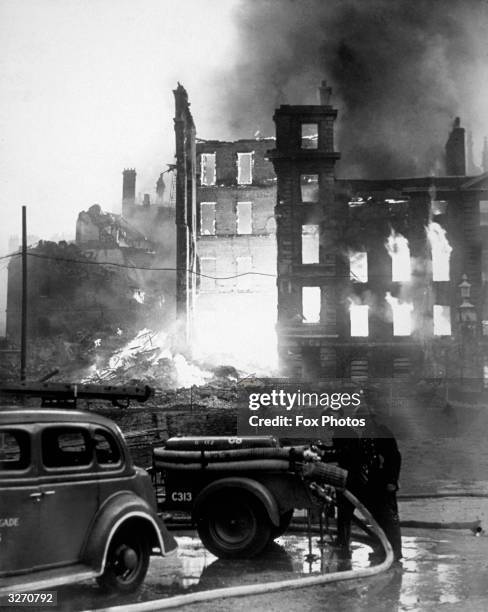 Firemen check their trailer pumps as the historic Temple Buildings burn in the background, following a German air raid on London.