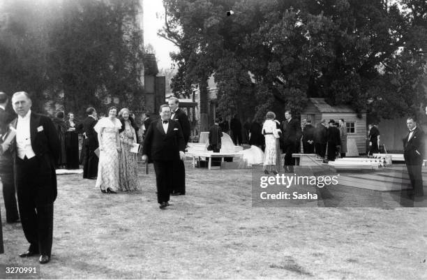 Opera-goers during an interval at the opening of the first Glyndebourne season. Pieces of scenery are lying on the lawn.