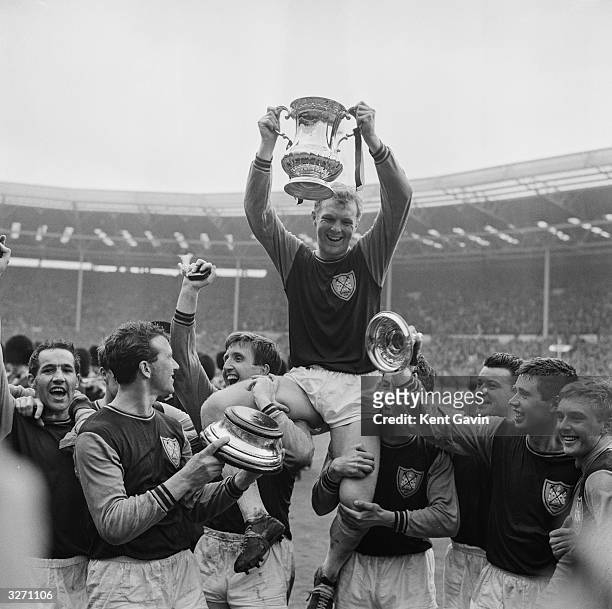 West Ham United captain Bobby Moore , holding the FA Cup, is held aloft by his team mates after their 3-2 victory over Preston North End in the FA...