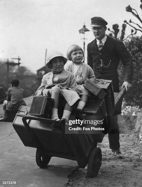 Railway porter shifts two children along with the luggage.