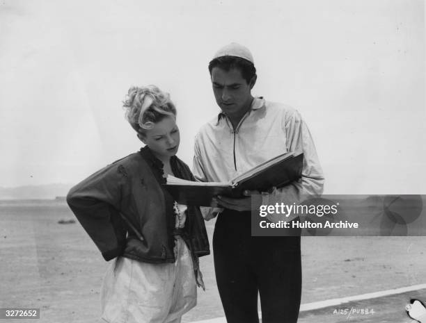 French leading lady Cecile Aubry looking over the script of the 20th Century Fox film 'The Black Rose' with co-star Tyrone Power , during location...