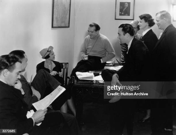German Director Fritz Lang is laughing and drinking coffee between scenes. Sylvia Sidney would love a cup but her physician has restricted her to one...