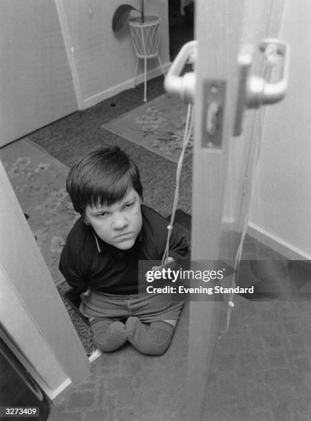 Year old thalidomide victim Eddie Freeman opens a door with a piece of string.