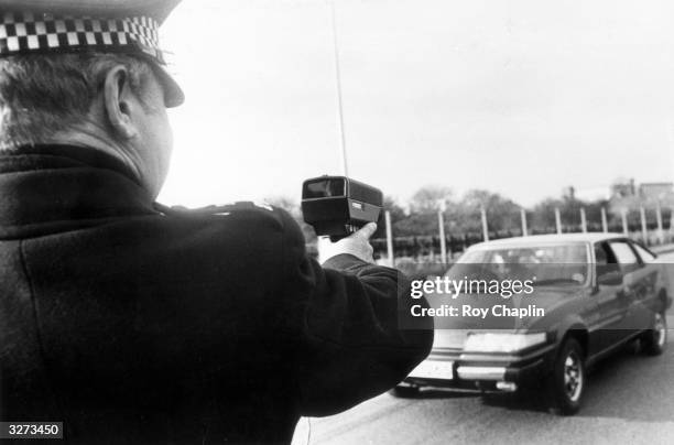 Alex McHattie aiming a radar speed gun at a car.