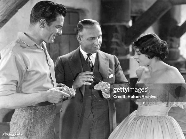 George Duryea , director Allan Dwan, and Renee Adoree look at some gold ore on the set of the MGM film 'Tide Of Empire', set at the time of the...