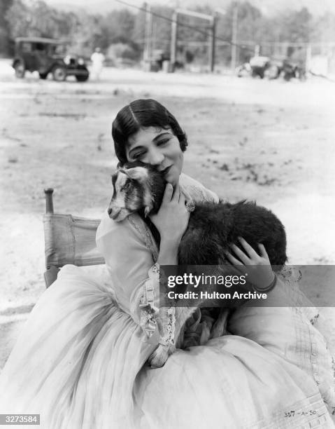 American actress Renee Adoree hugs a kid goat, the mascot, on the set of the film 'Tide Of Empire', directed by Allan Dwan for MGM.