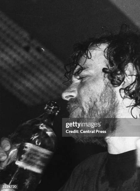 English folk singer Joe Cocker takes a swig of whisky during his performance while on tour in Australia.