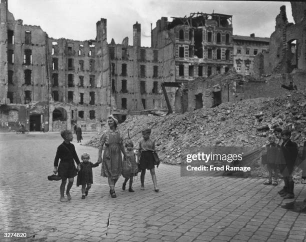 Elsa Gabriele passes by the battle ruins of Berlin as she accompanies her family to school.The boys carry their shoes to save on wear and tear.