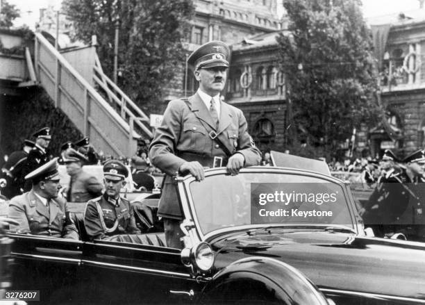 The Chancellor of Germany, Adolf Hitler standing in his car as he travels through the ancient town of Nuremberg to open the Nazi Congress. In the...