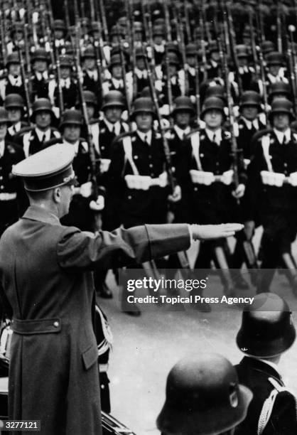 Goose-stepping Nazi troops receive a salute from Adolf Hitler .