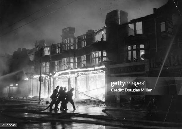 Firefighters direct jets of water onto the facade of Harrison and Gibson's furniture store in Ilford, Essex, which was completely gutted by fire.