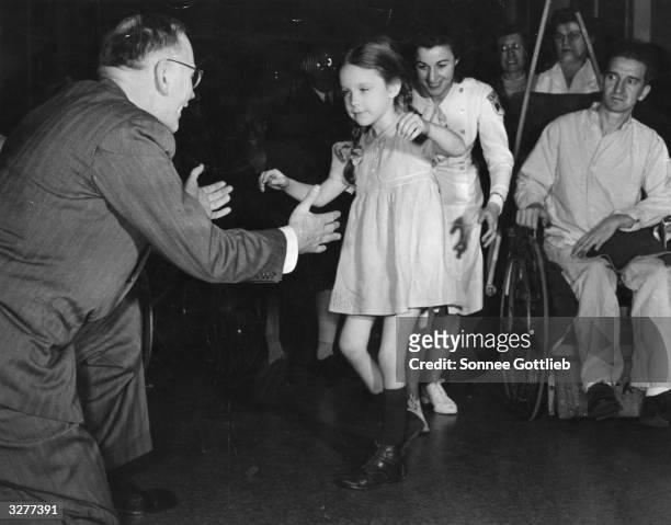 Five year old polio victim walks into the outstretched arms of Doctor George Deaver, faculty member of the New York University College of Medicine,...