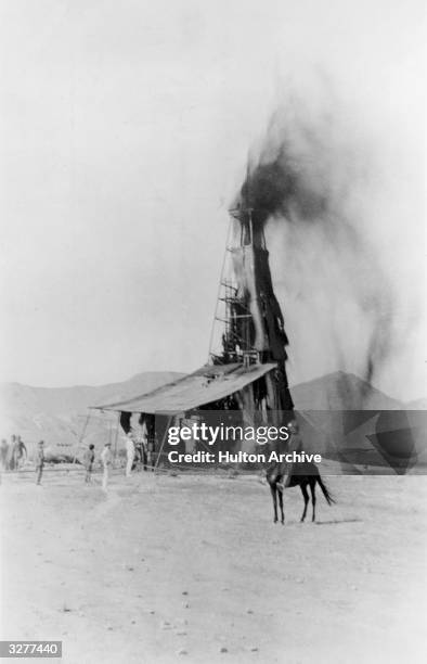 Oil flowing over a derrick from one of the first wells to be drilled at Masjid-i-Suleiman in Iran.