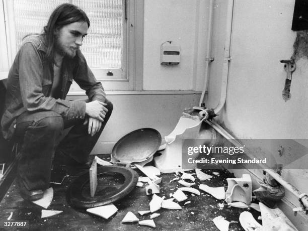 Year old John Read crouching amidst the destruction in a bathroom caused by the strong arm evictors of squatters at 44 Tadworth Square, Chelsea.