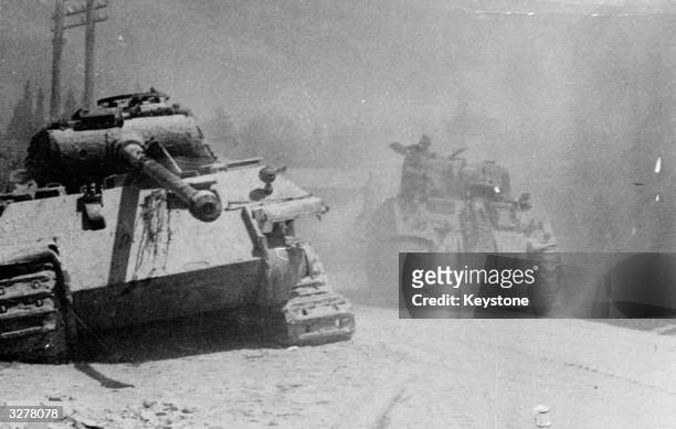 An allied Sherman Tank passing a knocked out German Panther tank during the advance on Arezzo, Italy.