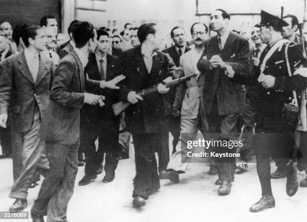 In Rome, an angry crowd of armed anti-Fascist civilians helps a policeman escort an ex-'Big Shot' of the Fascists to the jail where he will be held...