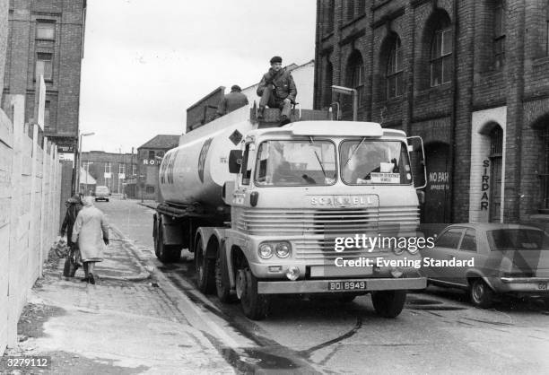 British soldier rides atop a petrol tanker as it travels down a back street during a strike in Northern Ireland.